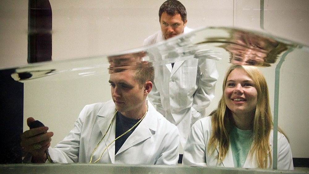 A professor monitors two graduate students while conducting a test in the wave tank simulator.