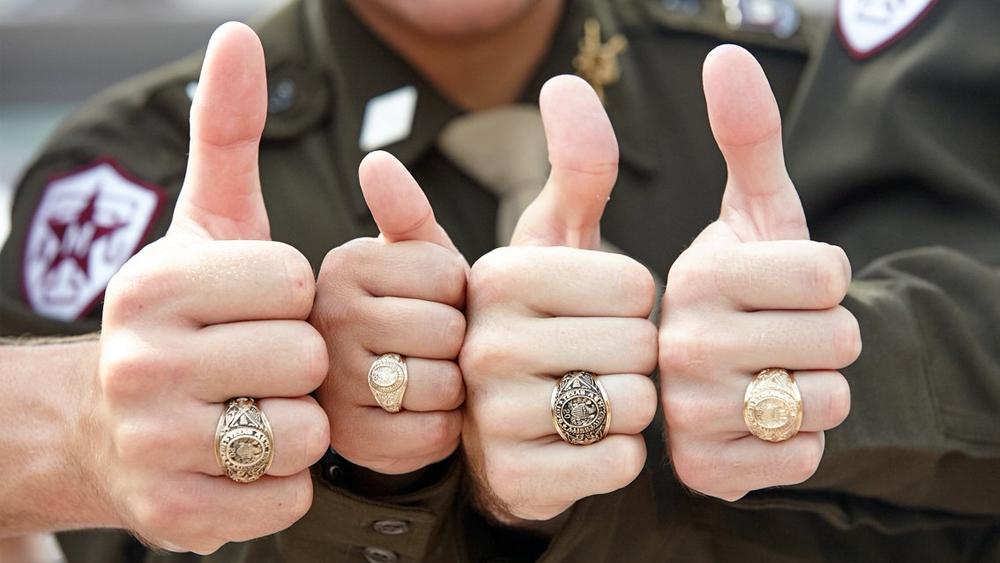 Four thumbs up with each wearing an Aggie ring.