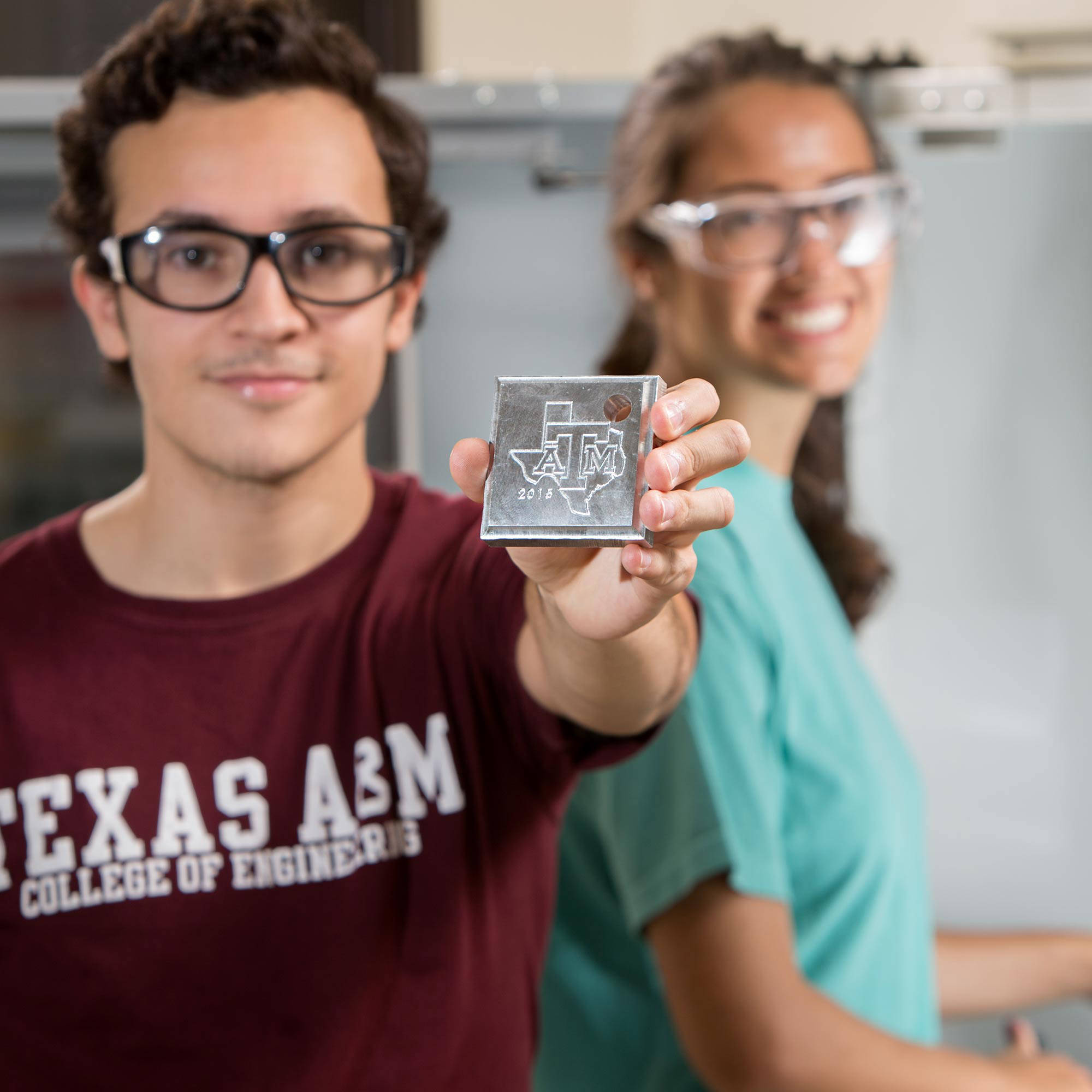 college of engineering student showing 3D printed A&amp;M logo