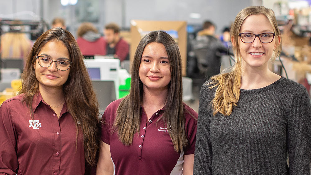 Three Aggie women engineering students standing together in a classroom.