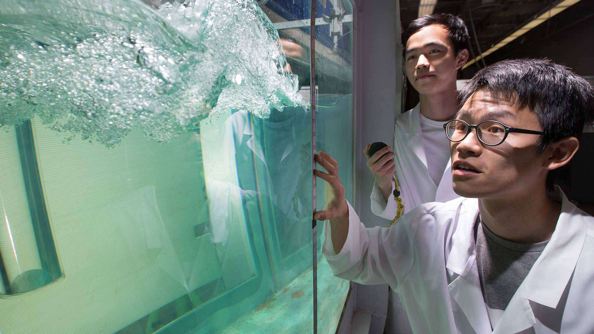 Two men in lab coats testing water flow.
