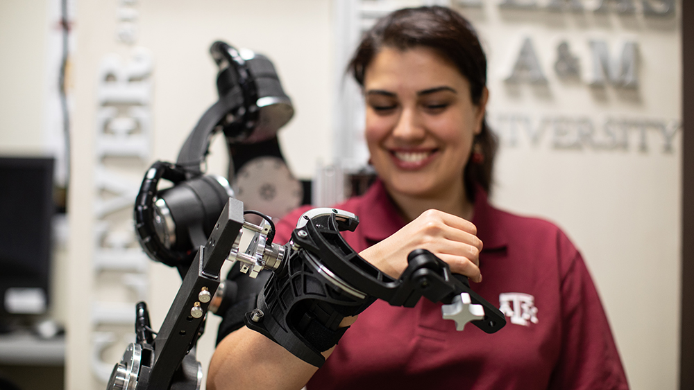Female student using a robotic arm device.