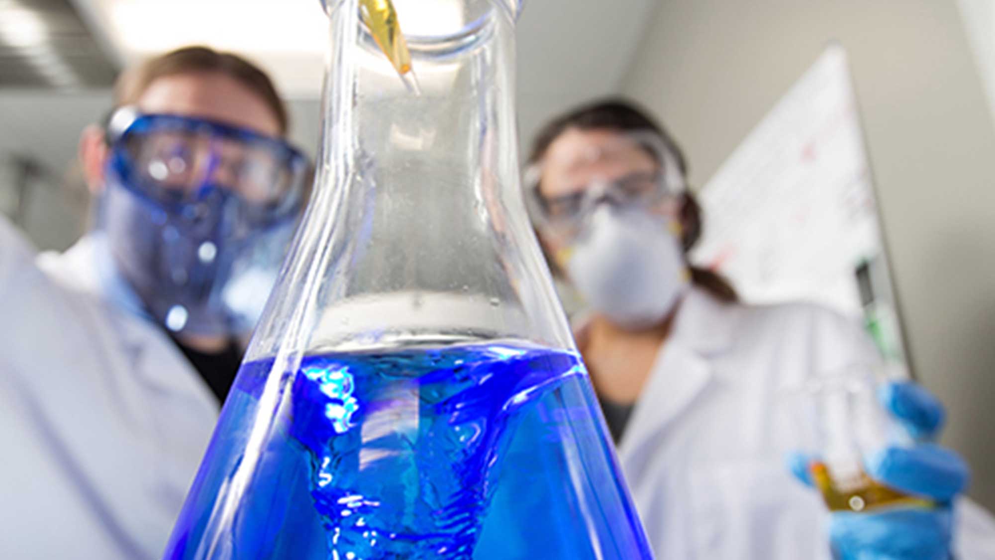 researchers testing fluids in a beaker