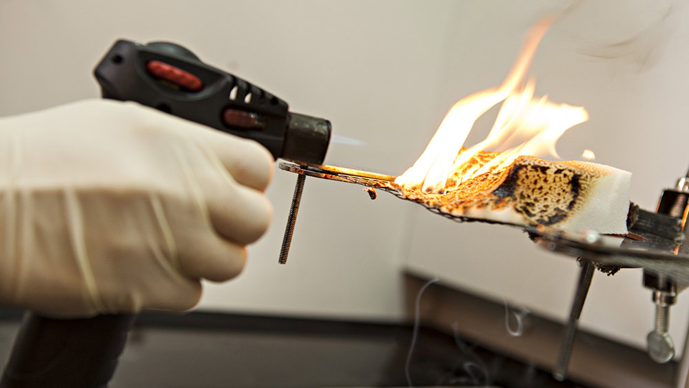 A blow-torch applying flame to a piece of foam