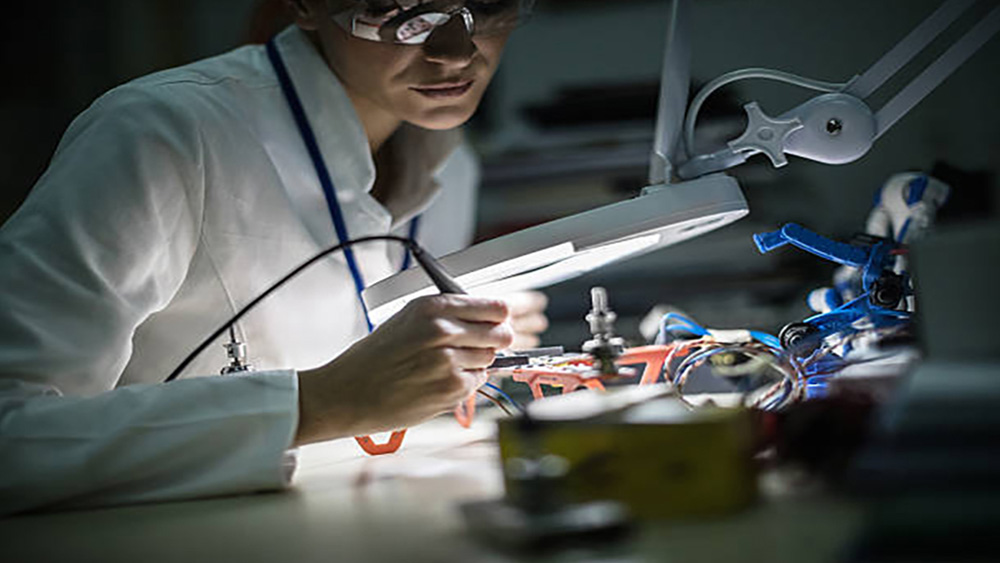 A woman in a lab coat working with a microscope doing research.   