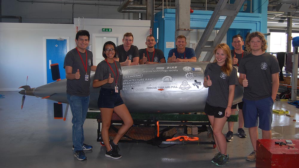 The team poses in front of their submarine named "Hullabalooga".