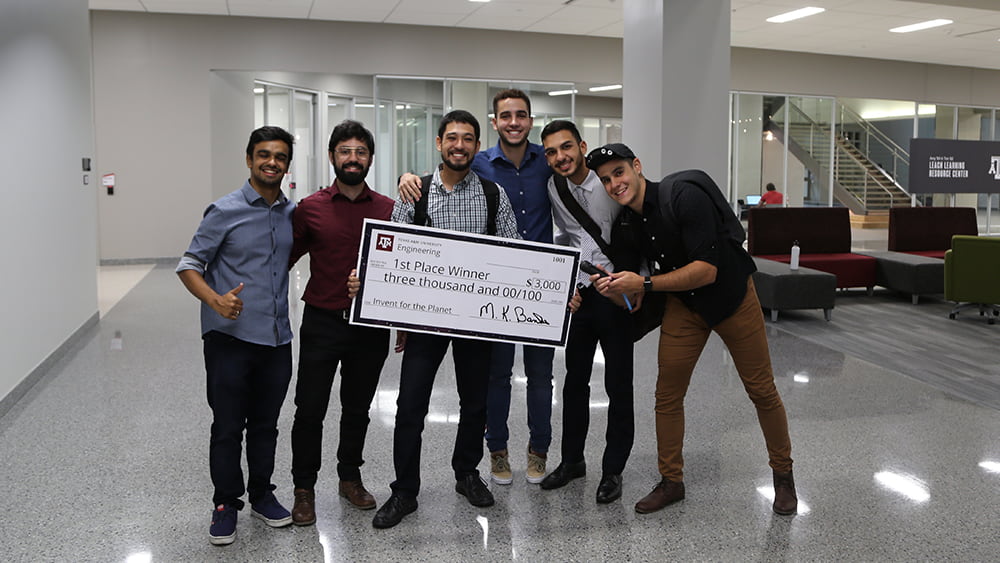 6 teammates from Brazil hold a check that says $3,000 - 1st place winner
