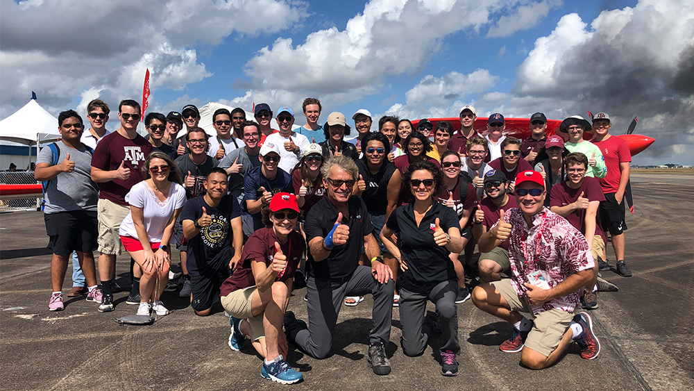 Texas A&M University Aerospace Engineering students gather for a group photo in front of Sean D. Tucker's Team Oracle Challenger III biplane at the Wings Over Houston Airshow.
