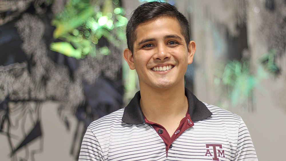 William Villalobos standing in front of artwork in Zachry Engineering Education Complex