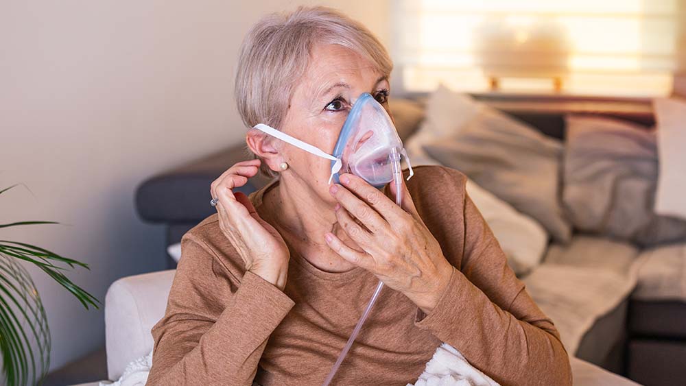 Old woman wearing an oxygen mask.
