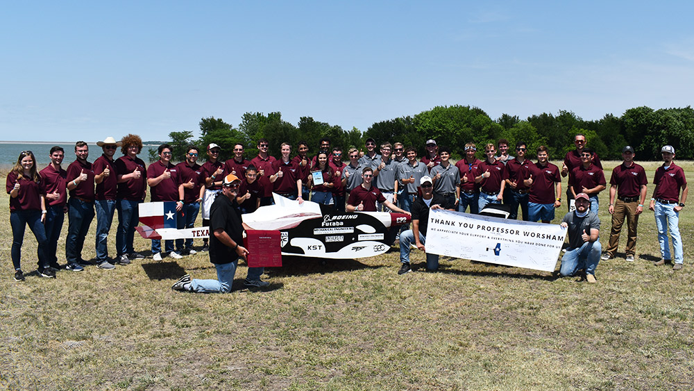 Group photo of the Texas A&M University SAE teams posed behind their two aircraft.