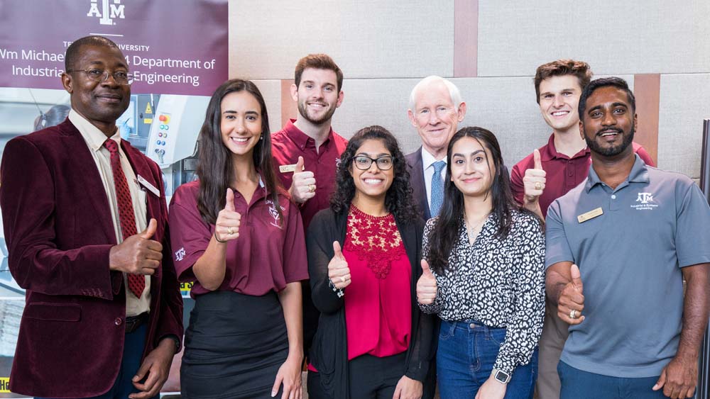A group of Texas A&M University students standing with Dr. Lewis Ntaimo and Dr. William Michael Barnes at the naming ceremony for the department.