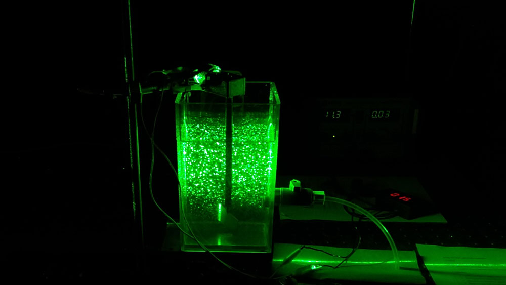 green laser on a jar filled with water, tubes and wires 