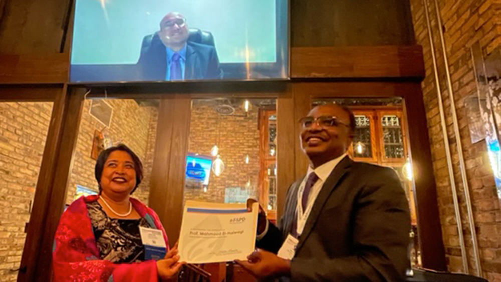 Dr. Nimir Elbashir (right) accepting the 2023 American Institute of Chemical Engineers’ Fuels and Petrochemicals Award from Dr. Debalina Sengupta. Dr. Mahmoud El-Halwagi attended virtually and can be seen on a large screen in the background.