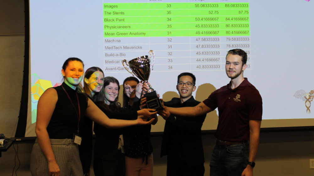 The winning team IMAGES and the 2023 Medical Device Make-A-Thon director hold the trophy together.