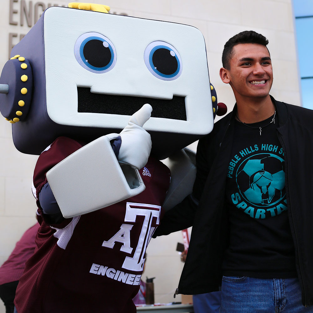 Sparky and young boy posing for a photo in front of Zachry Engineering building