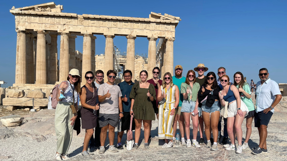 A group of study abroad students give the Aggie thumbs-up in front of the Parthenon in Athens, Greece.