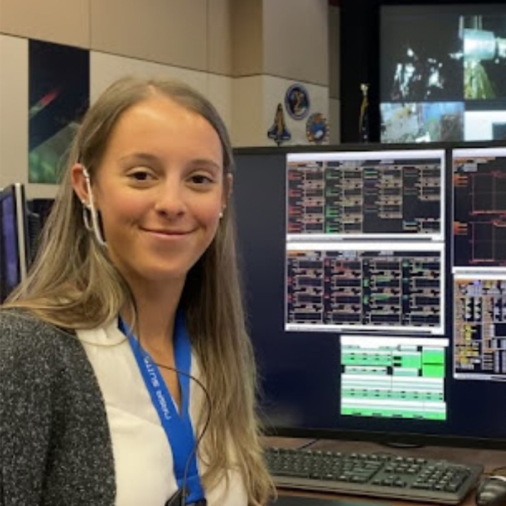 Leah Davis sitting in front of flight operations computers and TVs