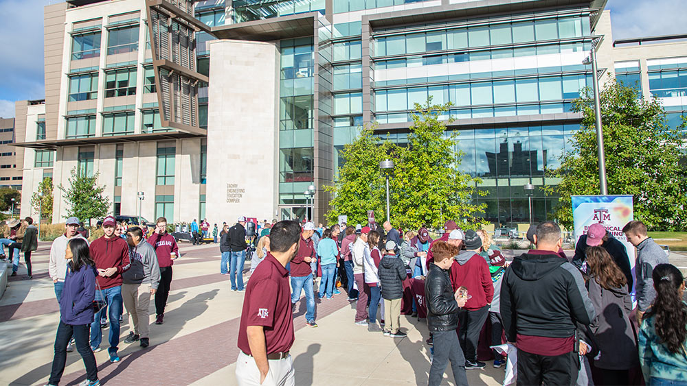 group of Aggie alumni gathering for an event in the courtyard of the Zachry building
