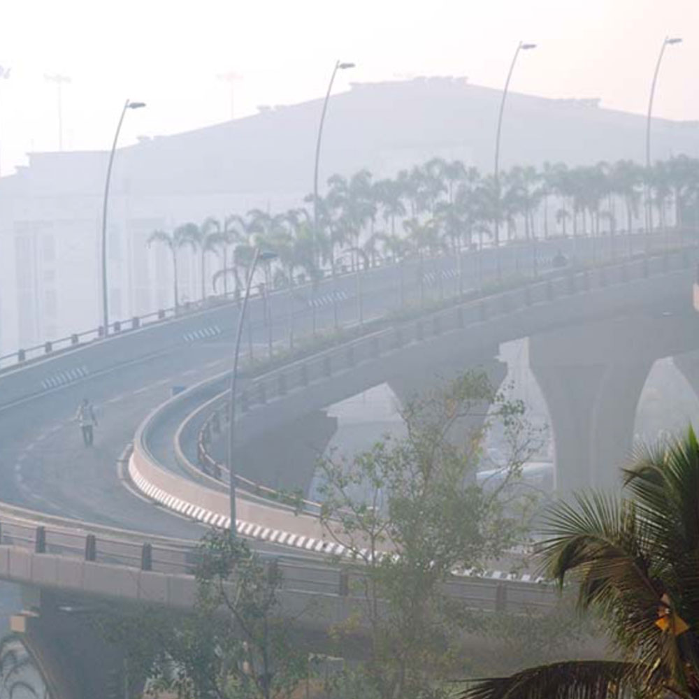 Hazy view of highway overpass with building silhouette in background 