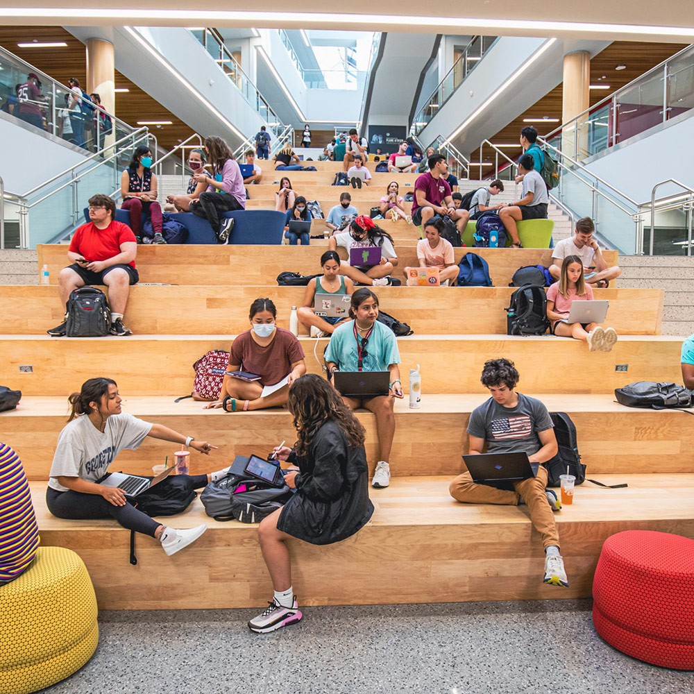 View of the learning stairs in Zachry. Students are seated in the seating area studying and relaxing.