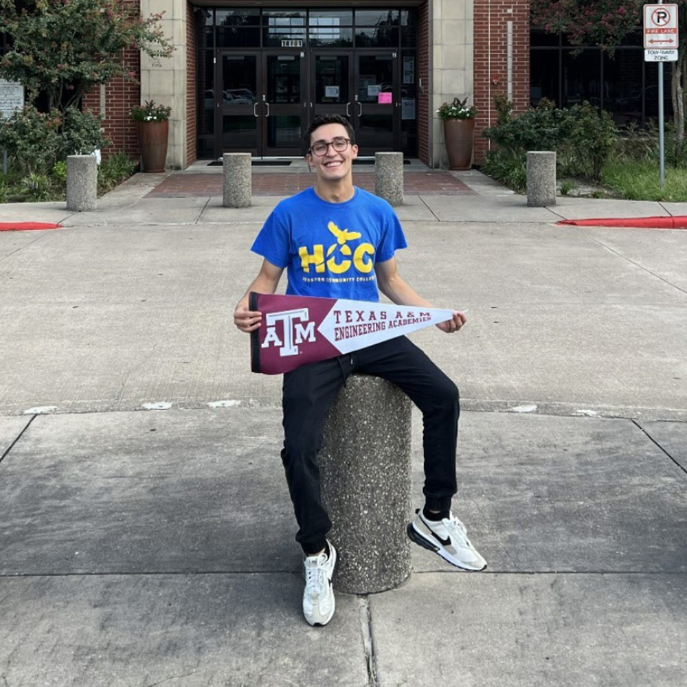 David Gonzalez standing outside Westside high school holding a Texas A&amp;M pennant flag.