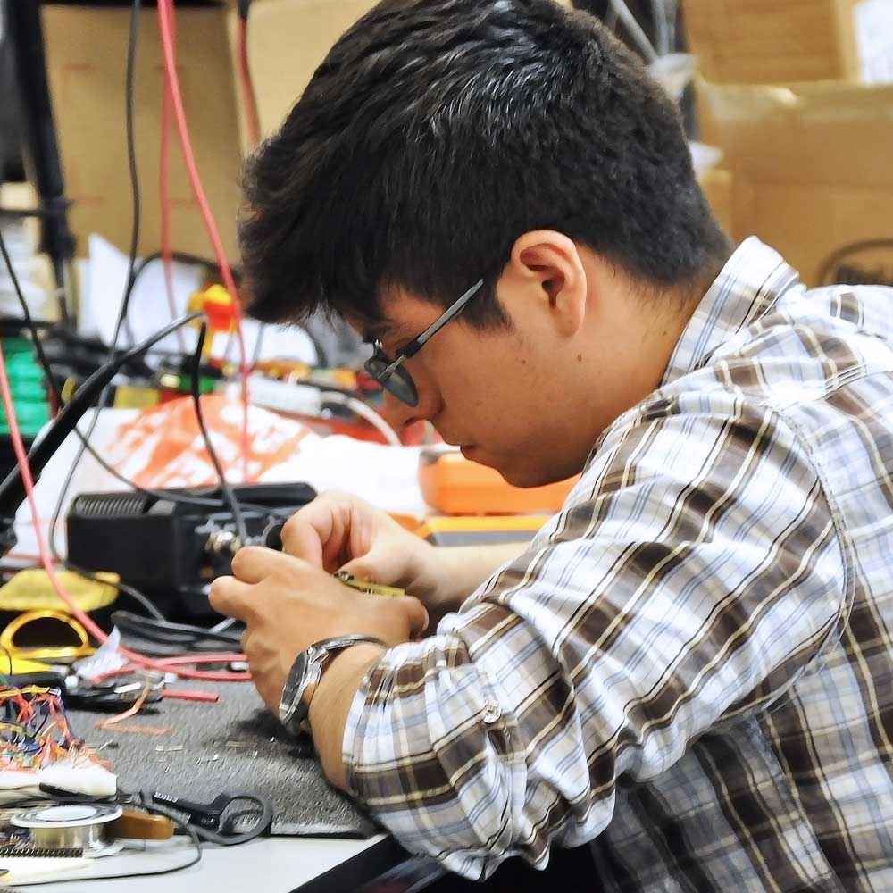 Male student sitting at a desk as he works on an engineering project.