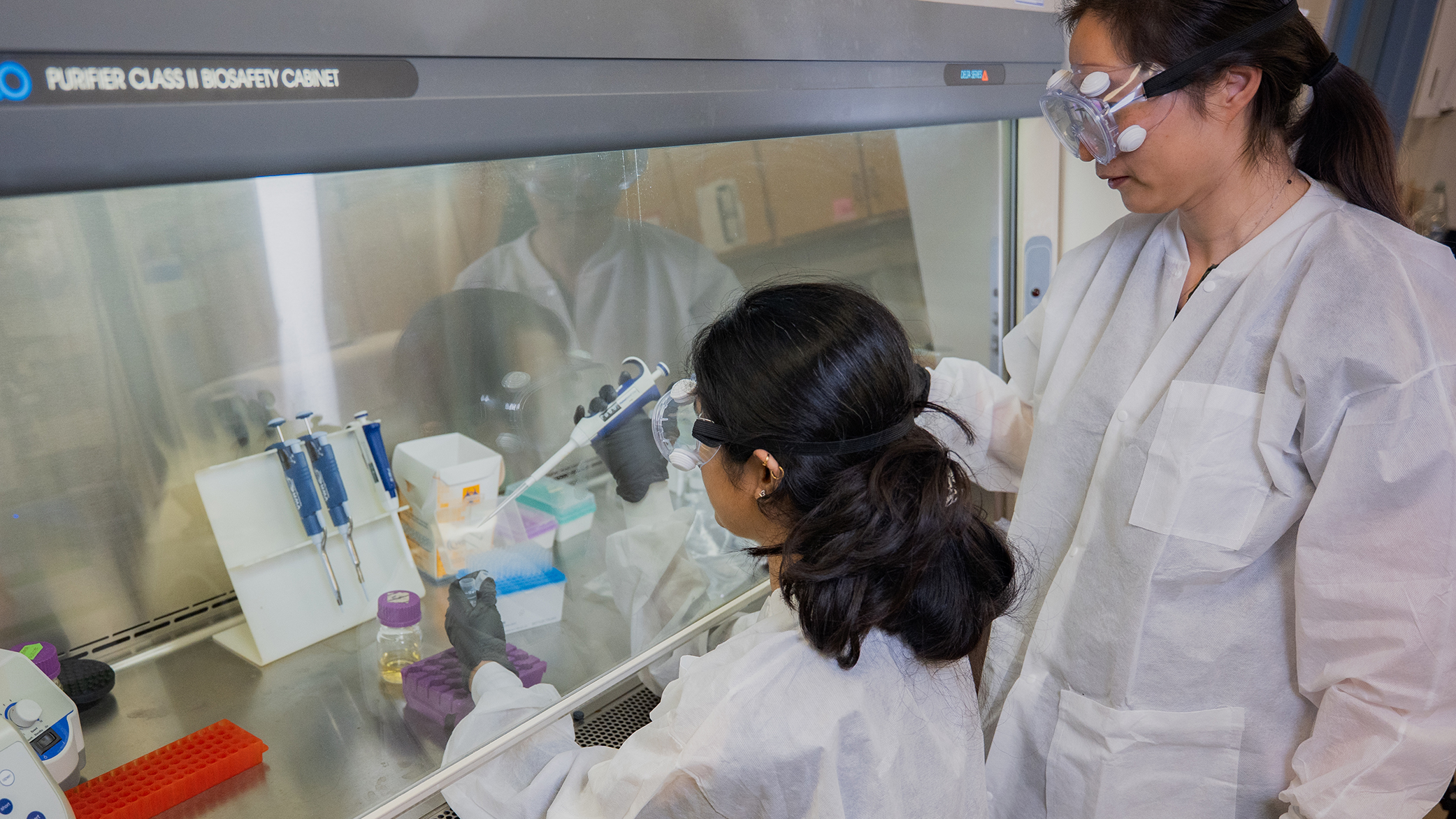 Instructor observes a student measuring out a liquid sample in a lab