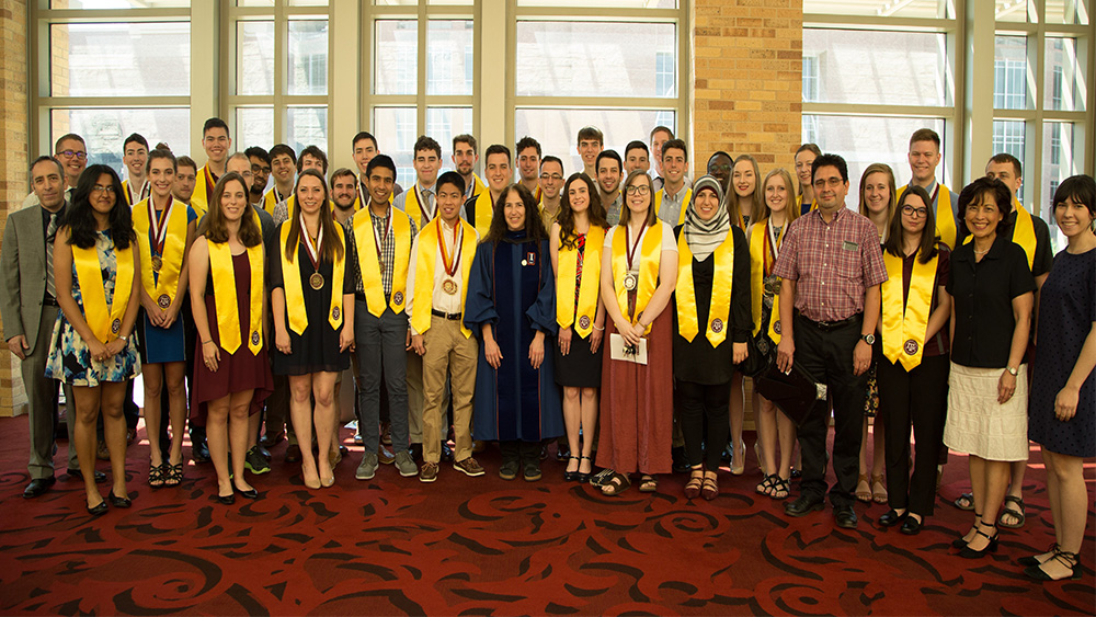 Group of graduating Engineering Honors students in graduation regalia pose for a photo.