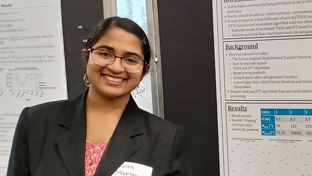 Tejini Murthy stands in front of poster presentation. 