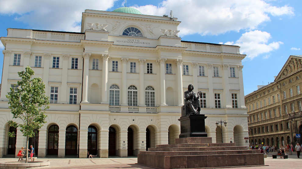 Black statue in front of white building with copper dome