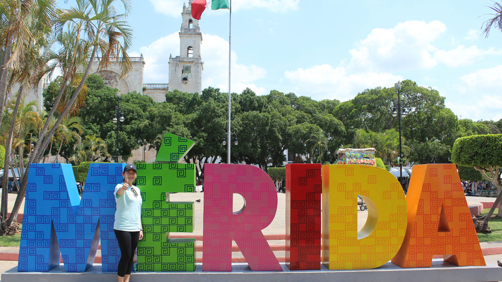Student in front of Mérida sign in Mexico.