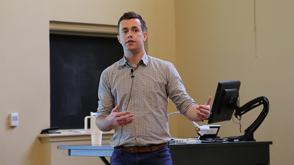 Person speaking while standing in front of a desk