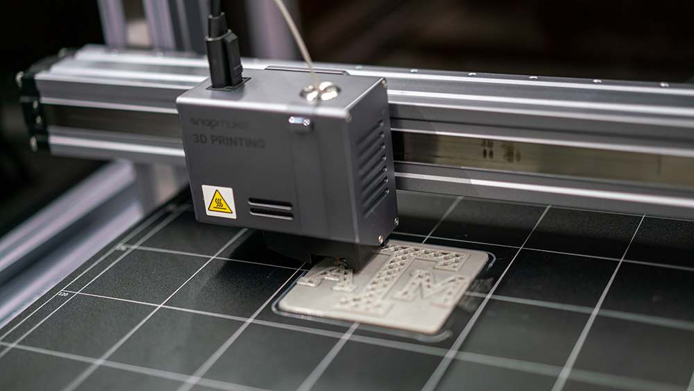 A 3D printer printing the block Texas A&amp;M logo.