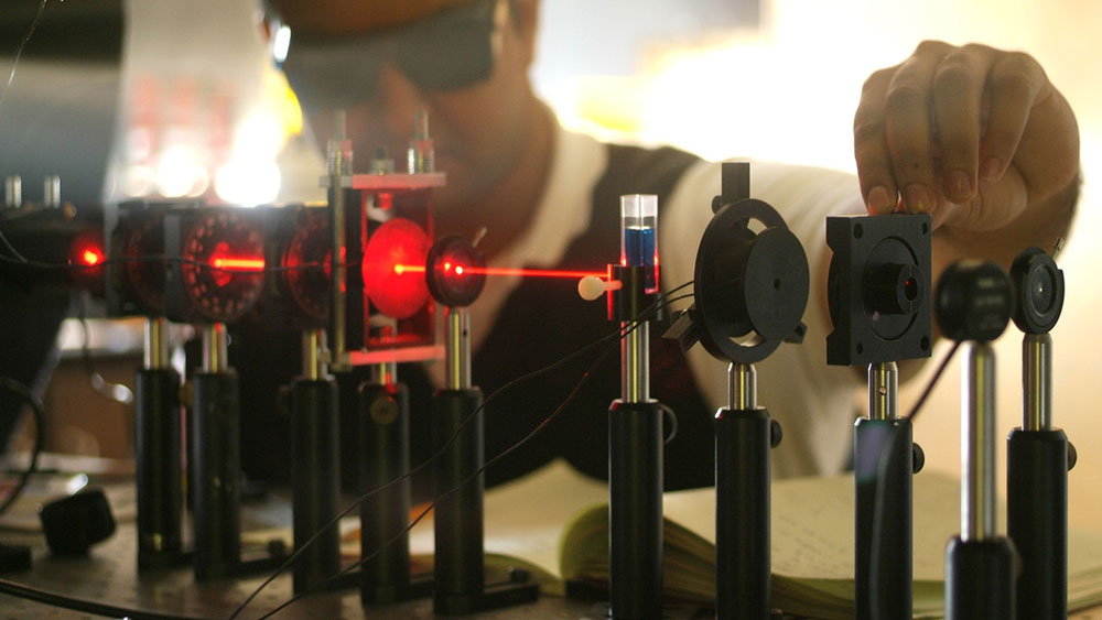 Man standing in front of red laser in lab