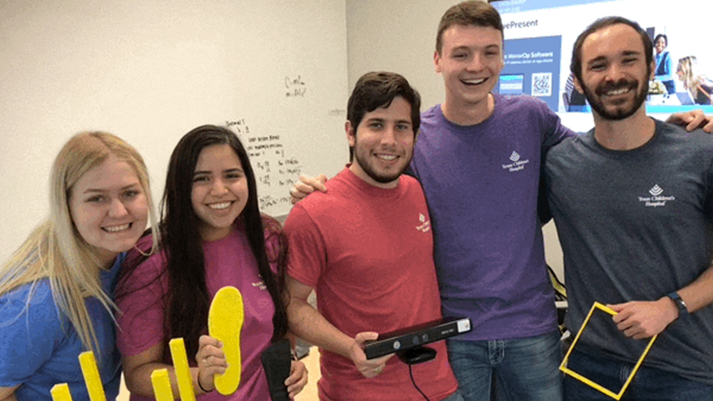 Five students smiling at camera, holding 3D printed foot orthotic prototype