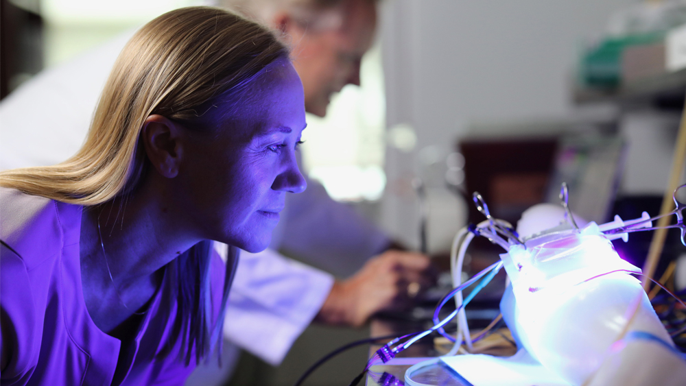 Female researcher looking at illuminated arm experiment