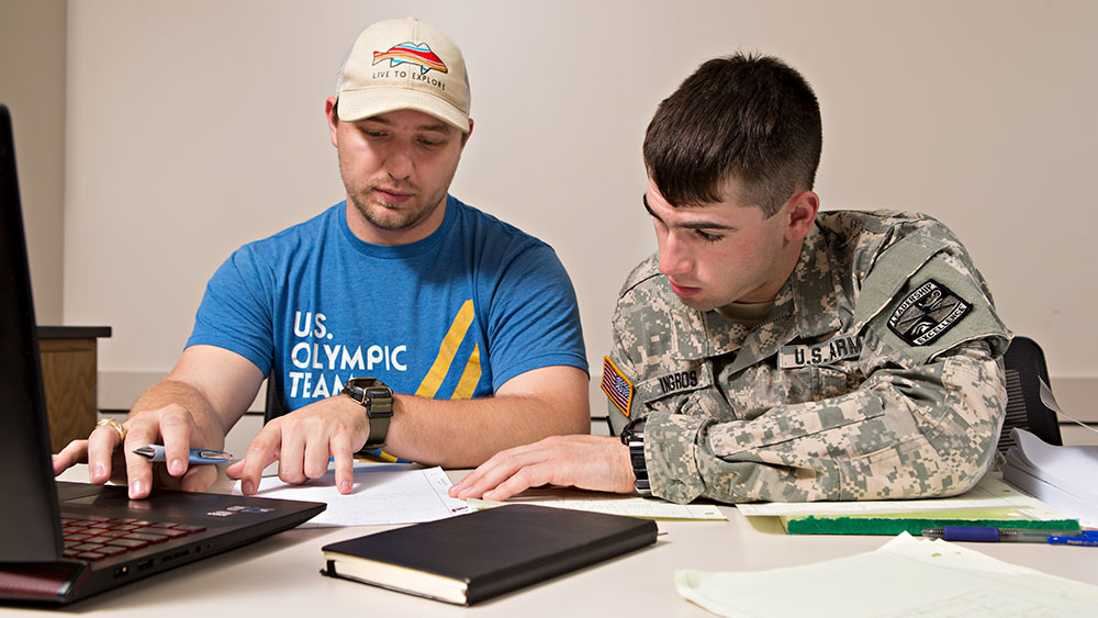 Two male students, one wearing US Army uniform studying together.