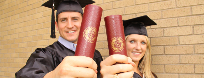Two students holding graduate degree after graduation ceremony