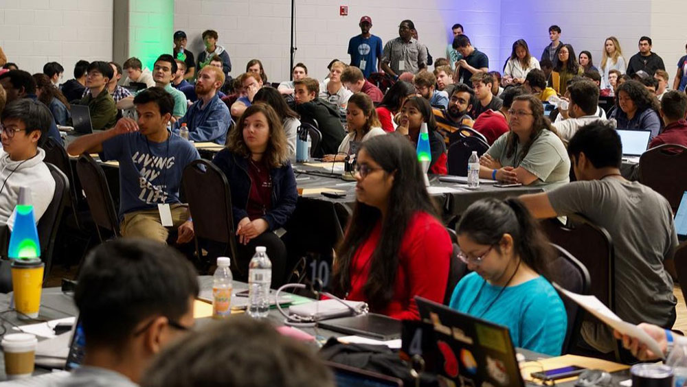 Students sitting at tables during a hackathon event.