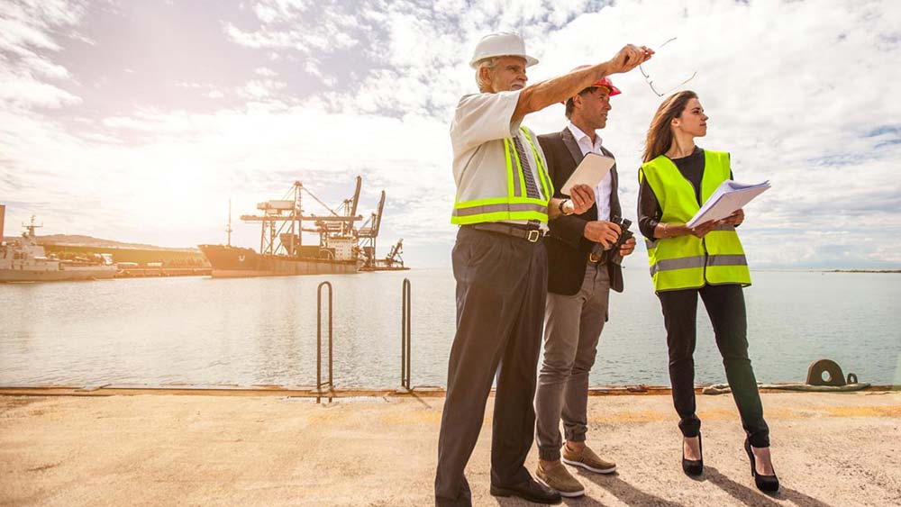 Industry workers pointing out something to a faculty member near an oil rig.