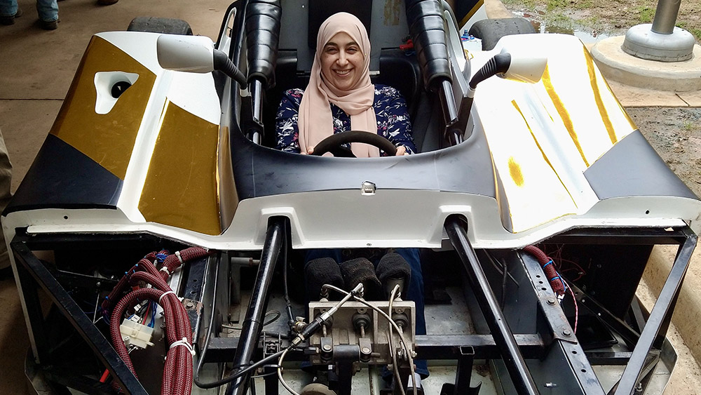 A smiling individual sits in a racecar.