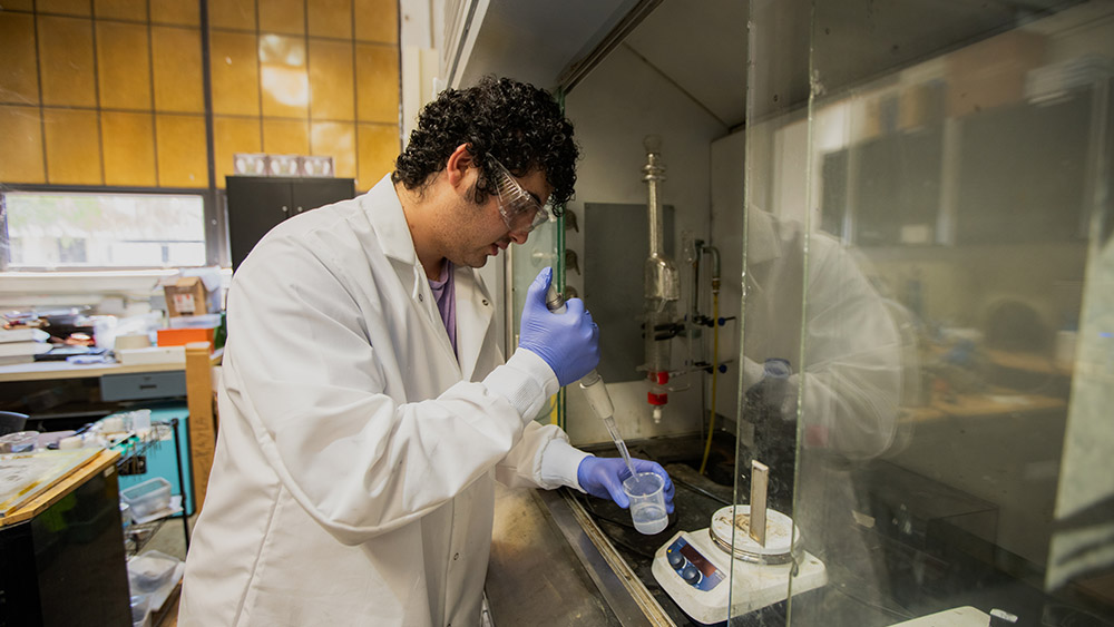 A student wearing safety glasses works in a lab.