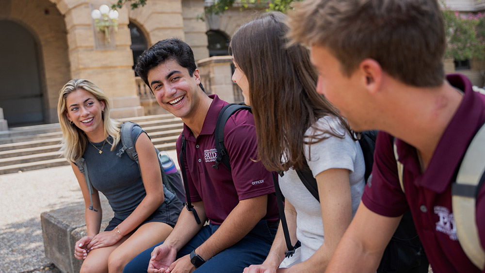 A group of four students smiling and talking.