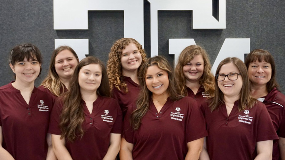 A group of eight individuals, all wearing matching polo shirts, each smiling at the camera.