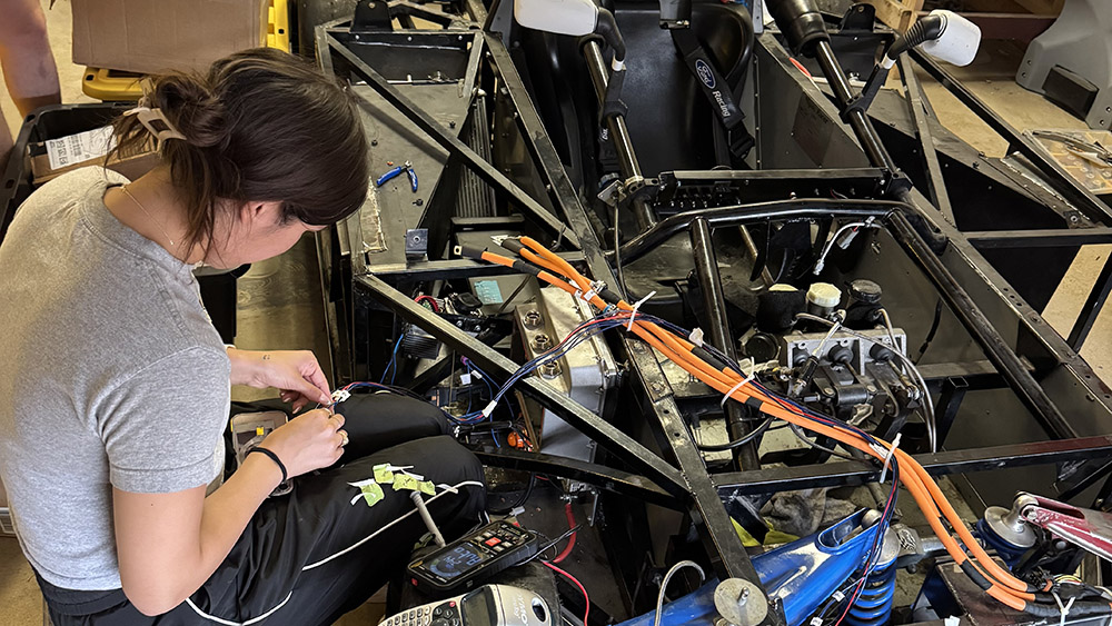 A student works on the electrical components of a racecar.