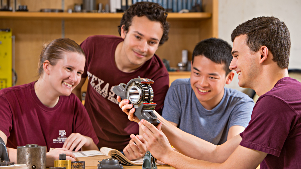Four undergraduate students study a manufacturing object.