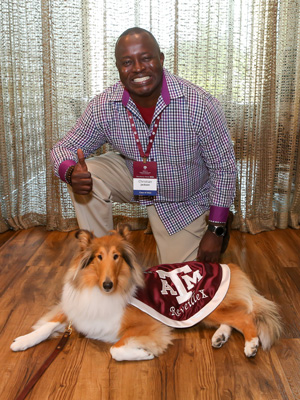 older male student of color smiling and posing with Reveille, the Texas A&amp;M University mascot