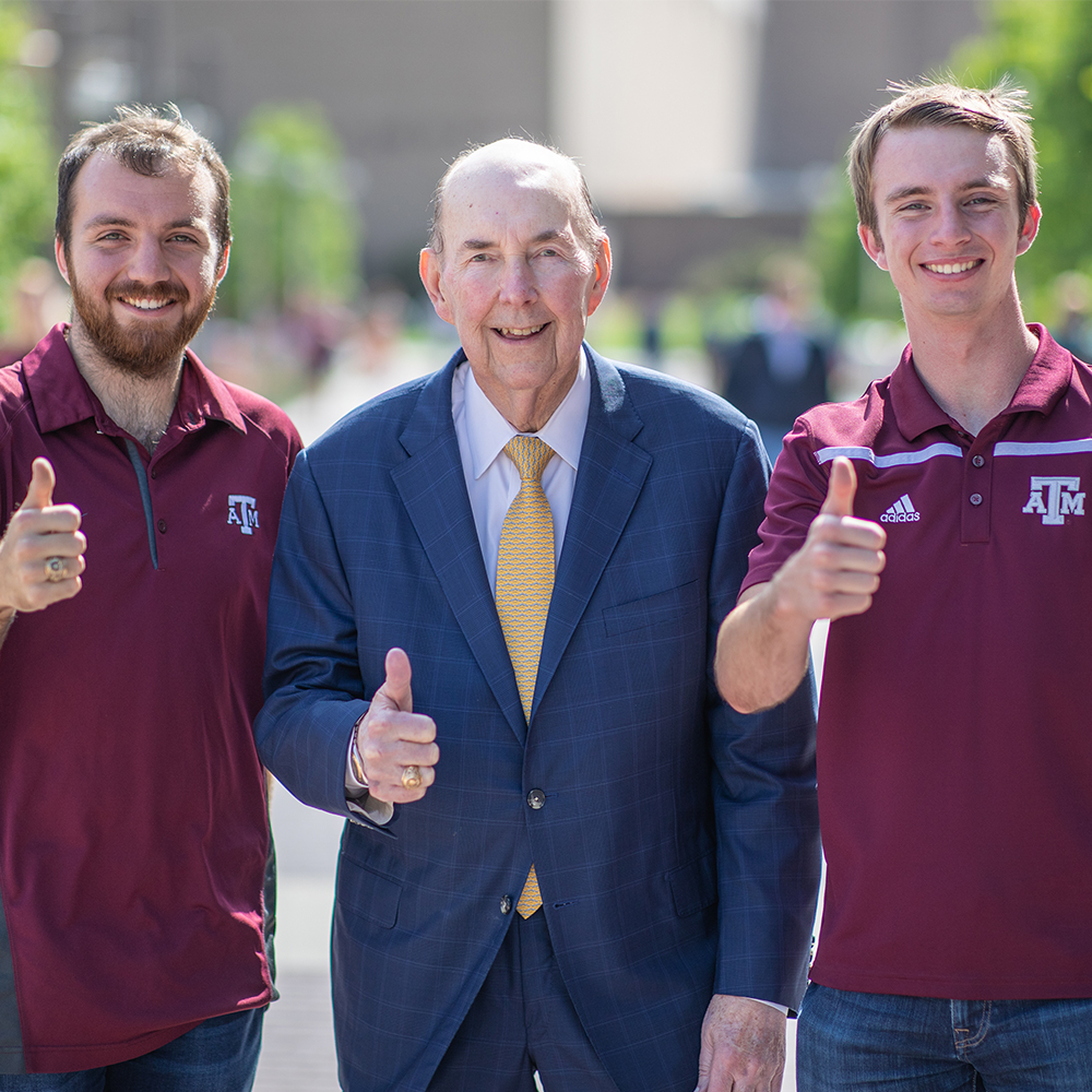 Earl Nye and his grandsons throw up a "Gig'em" on Engineering Walk