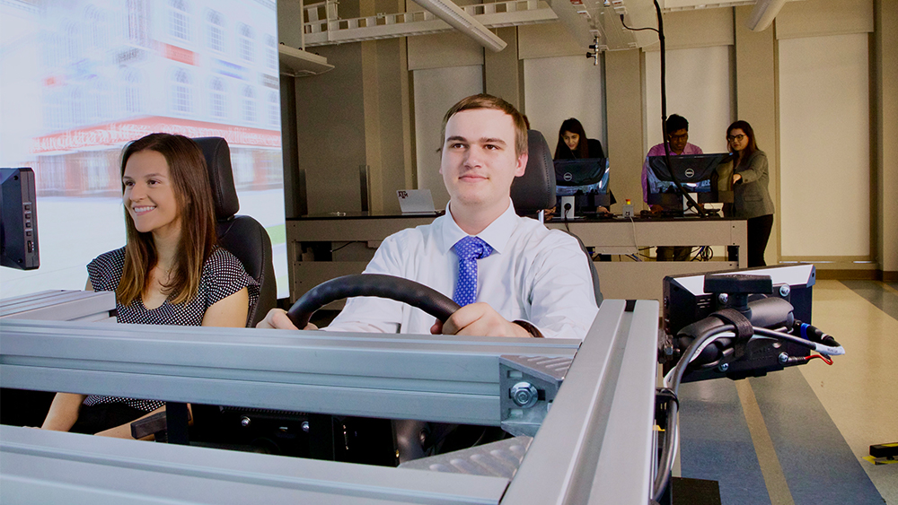 Two students sitting in driving simulator